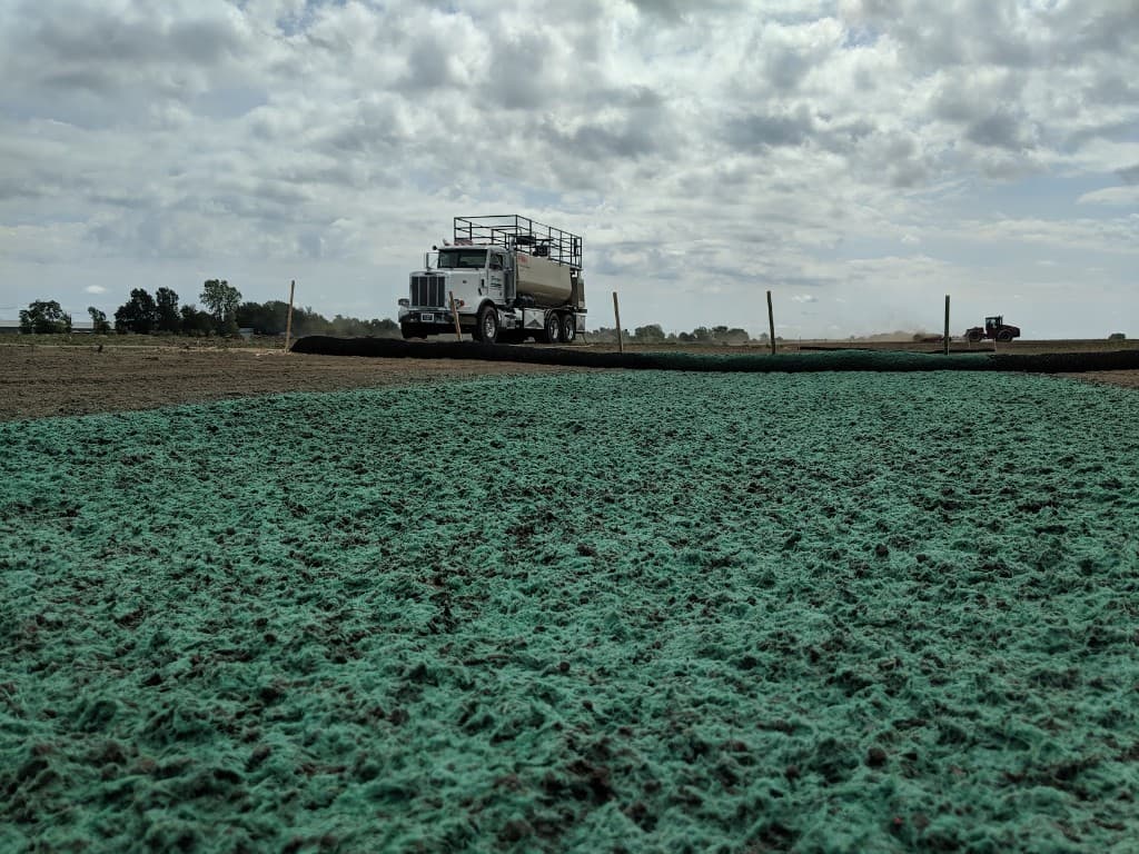 Hydroseeder truck on a large field covered with hydromulch for erosion control