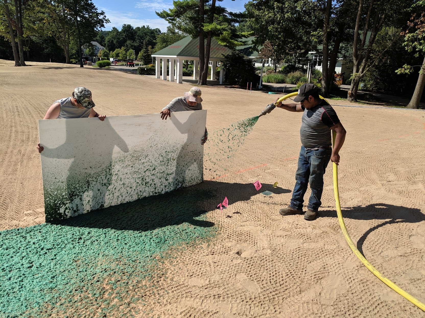 Crew spray-applying hydroseed onto a sand bunker at American Dunes golf course