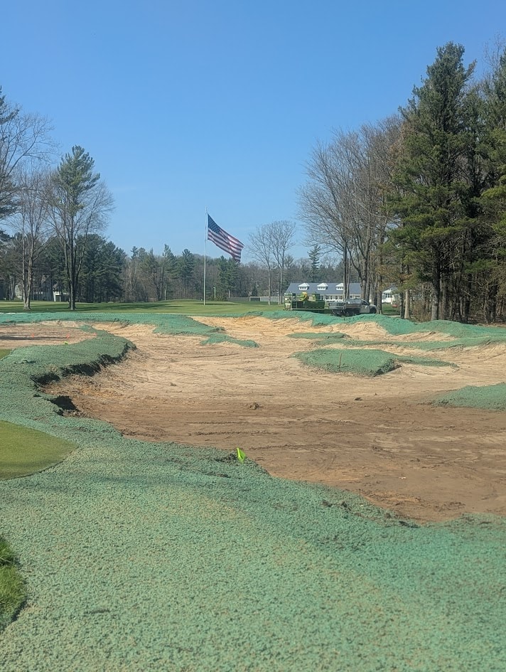 Bunker complex with green hydromulch and American flag at American Dunes golf course
