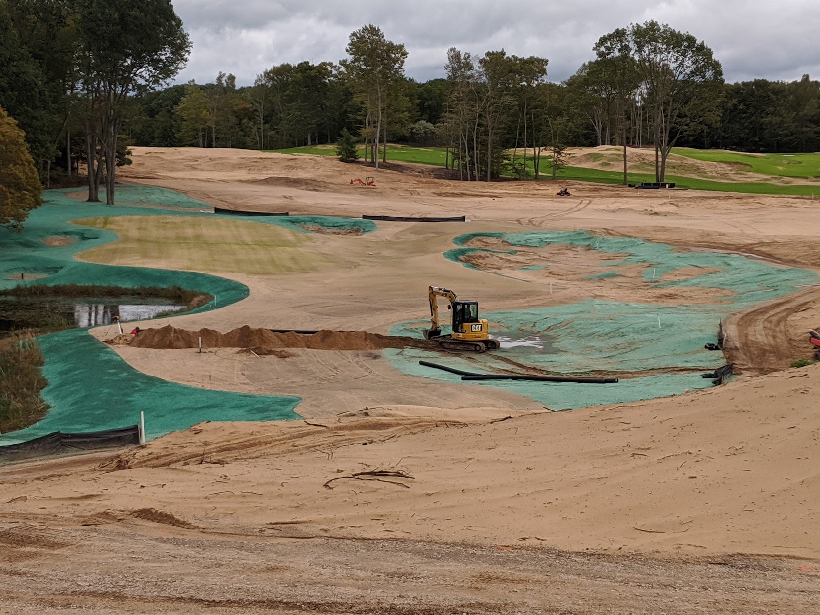 Excavator working on a hydromulched fairway and pond at American Dunes golf course