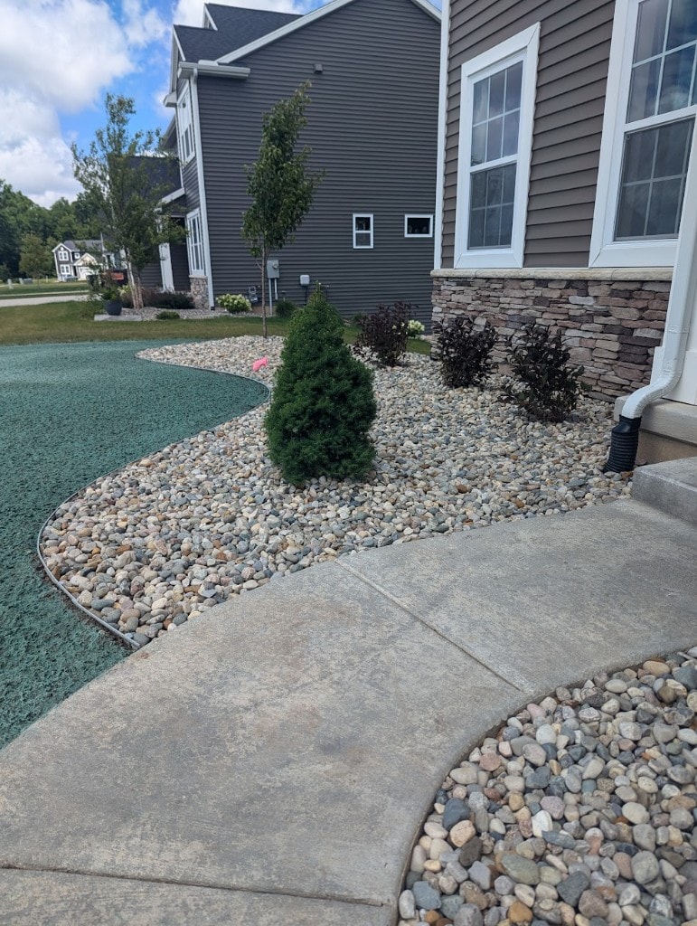 River stone landscape beds with plantings along a modern home